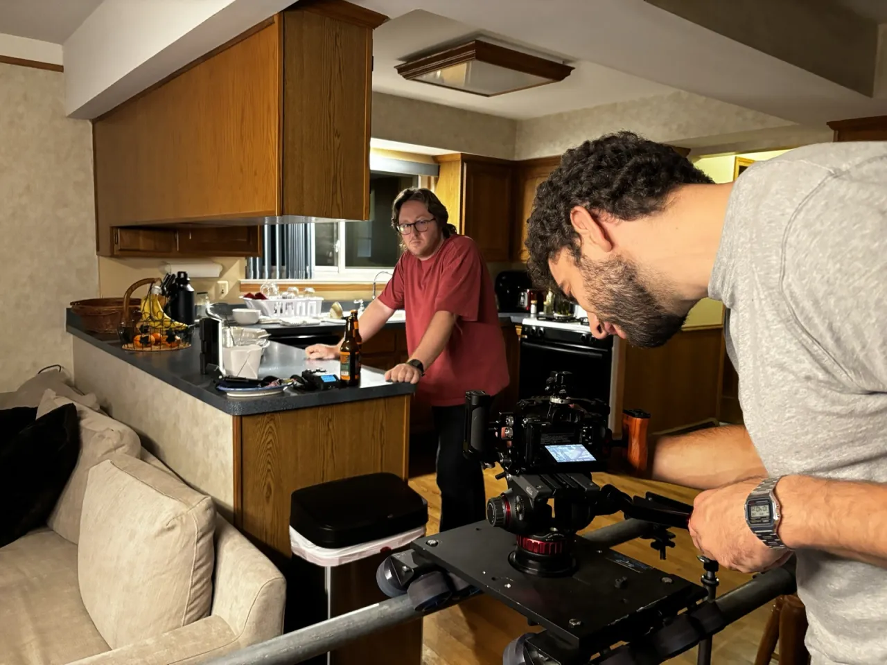 Kyle leans on the kitchen counter while Joe lines up a dolly shot