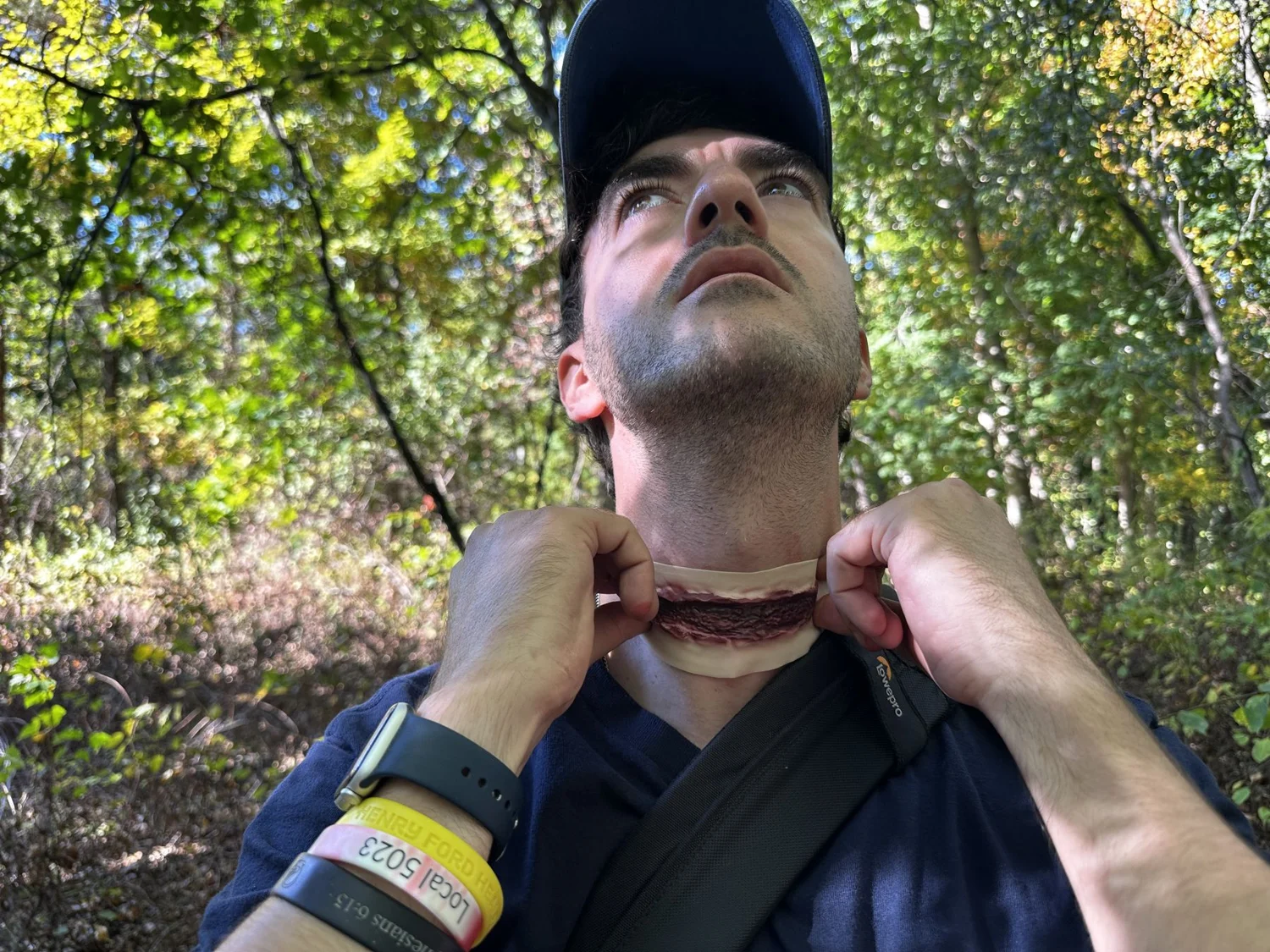 A performer adjusting his helmet strap in the woods