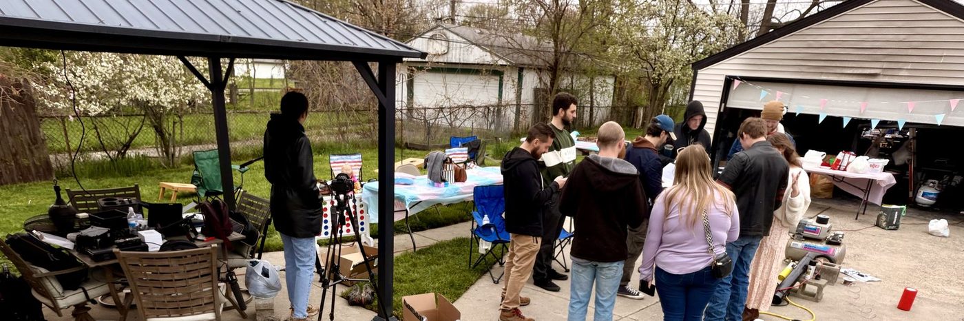 Gear cases, tripods and a folding table set up in a backyard on a shoot day.